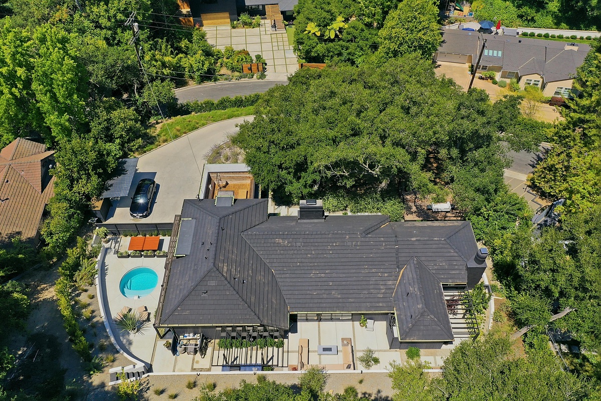 Top-down residential drone photo showing the home, pool, driveway, roofline, and surrounding trees