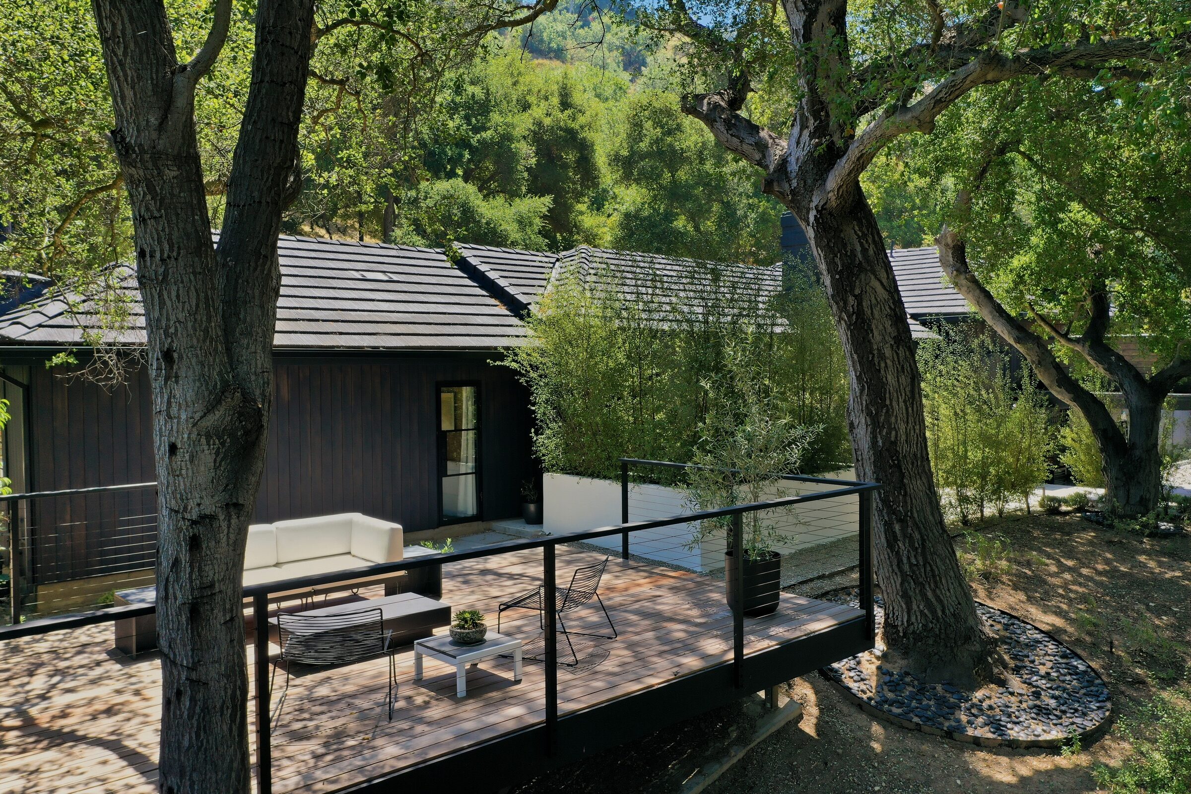 Drone view of a residential deck surrounded by mature trees
