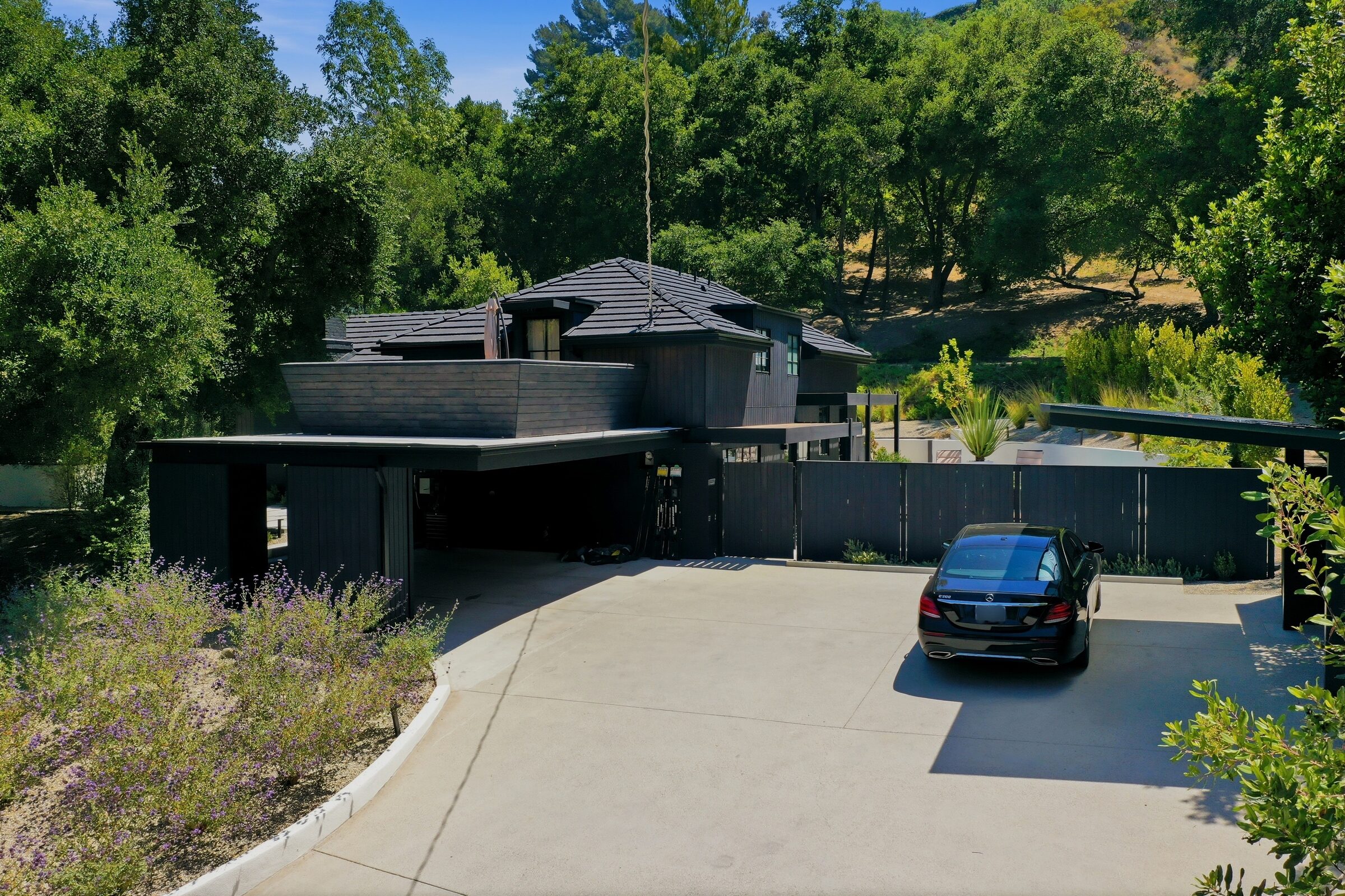 Drone view of a residential driveway and tree-lined hillside property approach
