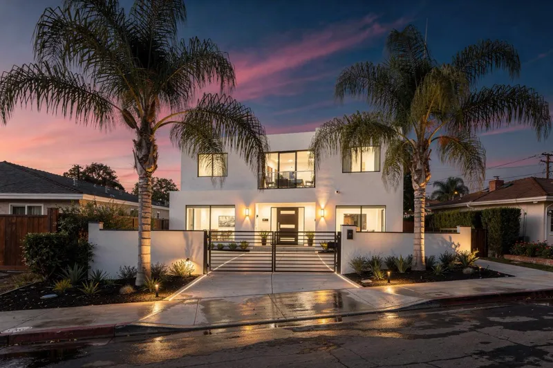 Modern residential home photographed at twilight with warm lighting and palm trees